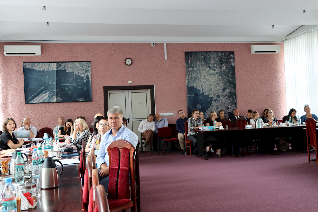 Kobiety i mężczyźni siedzą za stołami konferencyjnymi