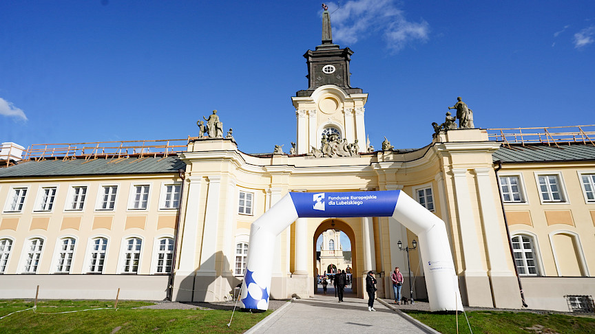Brama Pałacu Potockich w Radzyniu Podlaskim, przed którąś ustawiona jest dmuchana brama promująca Fundusze Europejskie