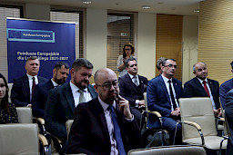 Na widowni przed rozpoczęciem konferencji siedzą na krzesłach Beneficjenci, którzy później odebrali umowy na realizację inwestycji unijnych. W tle stoi niebieski rollup Fundusze Europejskie dla Lubelskiego 2021-2027.
