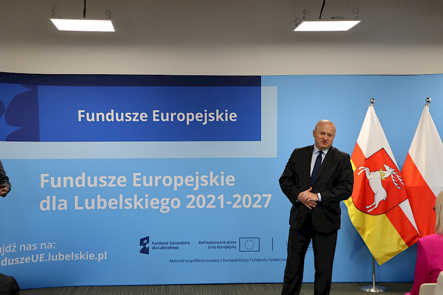 Marszałek Jarosław Stawiarski na tle niebieskiej ścianki Fundusze Europejskie udziela wywiadu dla Telewizji Polskiej przed uroczystą konferencją