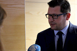 Mężczyzna w garniturze i okularach udziela wywiadu do mikrofonu.