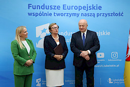 Marszałek Województwa Lubelskiego, Pan Jarosław Stawiarski wraz z Panią Anną Brzyską, Dyrektor Departamentu Zarządzania Programami Regionalnymi pozują  z Beneficjentką na tle ścianki promocyjnej  Fundusze Europejskie dla Lubelskiego