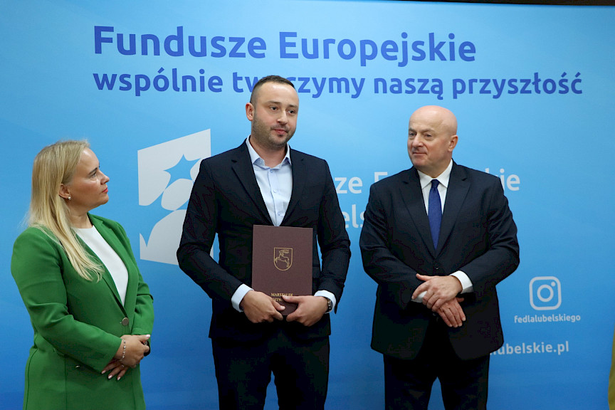 Marszałek Województwa Lubelskiego, Pan Jarosław Stawiarski wraz z Panią Anną Brzyską, Dyrektor Zarządzania Programami Regionalnymi pozują z Beneficjentem na tle ścianki promocyjnej  Fundusze Europejskie dla Lubelskiego