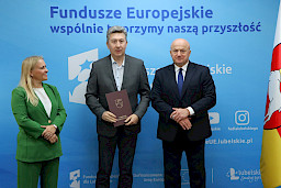 Marszałek Województwa Lubelskiego, Pan Jarosław Stawiarski wraz z Panią Anną Brzyską, Dyrektor Departamentu Zarządzania Programami Regionalnymi pozują  z Beneficjentem na tle ścianki promocyjnej  Fundusze Europejskie dla Lubelskiego.