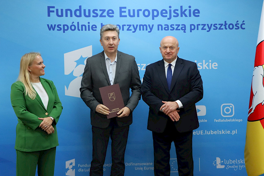 Marszałek Województwa Lubelskiego, Pan Jarosław Stawiarski wraz z Panią Anną Brzyską, Dyrektor Departamentu Zarządzania Programami Regionalnymi pozują  z Beneficjentem na tle ścianki promocyjnej  Fundusze Europejskie dla Lubelskiego.