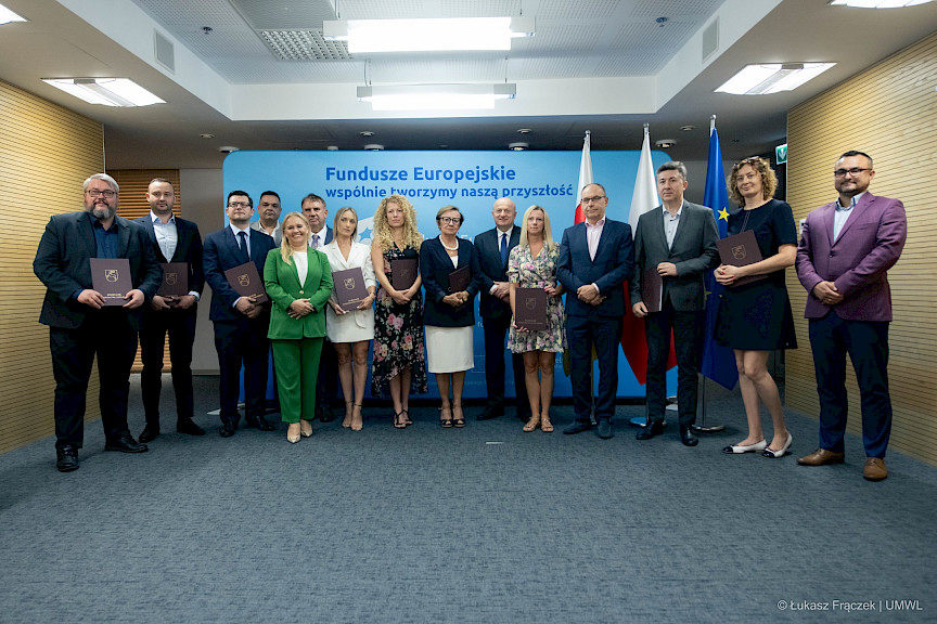 Zdjęcie grupowe Beneficjentów wraz z Panem Jarosławem Stawiarskim, Marszałkiem Województwa Lubelskiego i Panią Anną Brzyską, Dyrektor Departamentu Zarządzania Programami Regionalnymi po wręczeniu umów na tle ścianki promocyjnej  Fundusze Europejskie dla Lubelskiego.