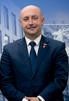 Zdjęcie profilowe Wicemarszałka Województwa Piotra Bresia. Ubrany w granatowy garnitur, granatowy krawat i białą koszulę.