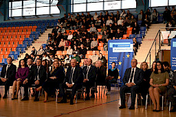 Uroczyste wręczenie umów z Działania 10.4 w Radzyniu Podlaskim w dniu 21.10.2024 r. Wszyscy zgromadzeni beneficjenci siedzą na krzesłach na sali gimnastycznej. za nimi siedzą zgromadzeniu uczniowie szkoły.