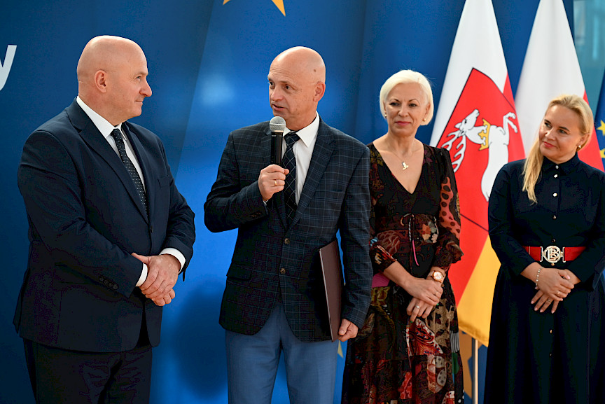Uroczyste wręczenie umów z Działania 10.4 w Radzyniu Podlaskim w dniu 21.10.2024 r. Na tle ścianki funduszy europejskich stoi Marszałek Jarosław Stawiarski oraz beneficjent z wręczoną umową.