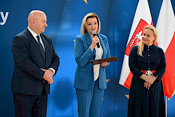Uroczyste wręczenie umów z Działania 10.4 w Radzyniu Podlaskim w dniu 21.10.2024 r. Na tle ścianki funduszy europejskich stoi Marszałek Jarosław Stawiarski oraz beneficjent z wręczoną umową.