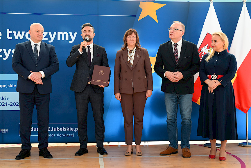 Uroczyste wręczenie umów z Działania 10.4 w Radzyniu Podlaskim w dniu 21.10.2024 r. Na tle ścianki funduszy europejskich stoi Marszałek Jarosław Stawiarski oraz beneficjent z wręczoną umową.
