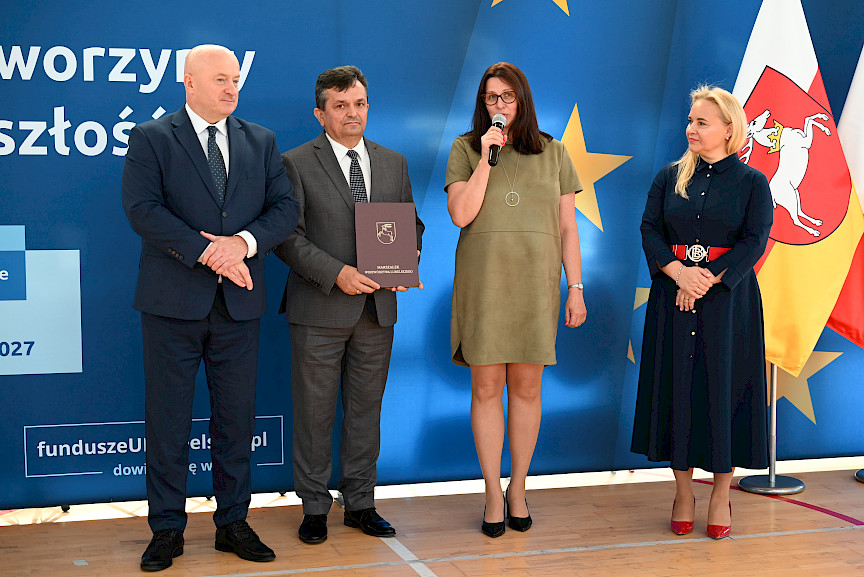 Uroczyste wręczenie umów z Działania 10.4 w Radzyniu Podlaskim w dniu 21.10.2024 r. Na tle ścianki funduszy europejskich stoi Marszałek Jarosław Stawiarski oraz beneficjent z wręczoną umową.