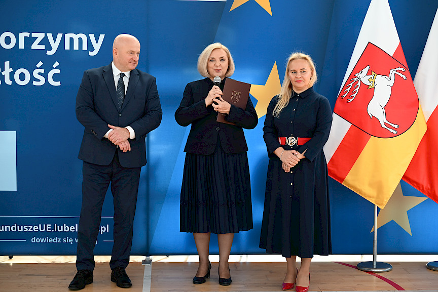 Uroczyste wręczenie umów z Działania 10.4 w Radzyniu Podlaskim w dniu 21.10.2024 r. Na tle ścianki funduszy europejskich stoi Marszałek Jarosław Stawiarski oraz beneficjent z wręczoną umową.