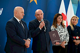 Uroczyste wręczenie umów z Działania 10.4 w Radzyniu Podlaskim w dniu 21.10.2024 r. Na tle ścianki funduszy europejskich stoi Marszałek Jarosław Stawiarski oraz beneficjent z wręczoną umową.