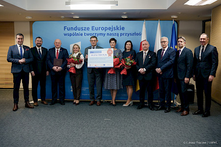 Podpisanie tysięcznej umowy dofinansowanej z Funduszy Europejskich dla Lubelskiego 2021-2027. Na tle ścianki funduszy europejskich Zarząd Województwa Lubelskiego oraz beneficjent 1000 umowy.
