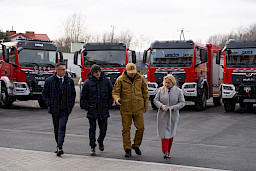Uroczyste przekazanie sprzętu Straży Pożarnej w Kraśniku, zaproszeni goście oglądają wręczone wozy strażackie.
