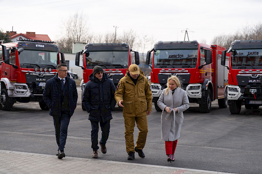 Uroczyste przekazanie sprzętu Straży Pożarnej w Kraśniku, zaproszeni goście oglądają wręczone wozy strażackie.