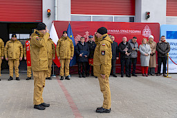 Uroczyste przekazanie sprzętu Straży Pożarnej w Kraśniku, strażacy meldują dowódcy otrzymanie wozów, w tle zaproszeni goście.