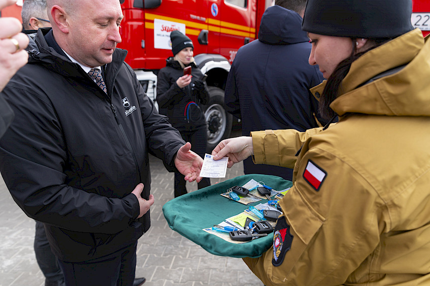 Uroczyste przekazanie sprzętu Straży Pożarnej w Kraśniku, Wicemarszałek Piotr Breś wręcza kluczyki oraz dokumenty do wozu strażackiego.