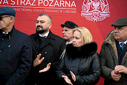 UroczyUroczyste wręczenie sprzętu Straży Pożarnej. Zebrani goście na tle garaży straży pożarnej w zamościu.ste wręczenie sprzętu Straży Pożarnej. Strażacy stojący przed przekazywanymi wozami strażackimi.