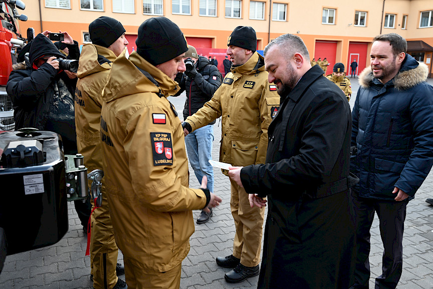 Uroczyste wręczenie sprzętu Straży Pożarnej. Członek Zarządu Województwa Lubelskiego wręcza strażakowi kluczyki do przekazywanego wozu bojowego.