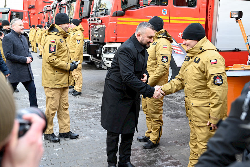 Uroczyste wręczenie sprzętu Straży Pożarnej. Członek Zarządu Województwa Lubelskiego wręcza strażakowi kluczyki do przekazywanego wozu bojowego.