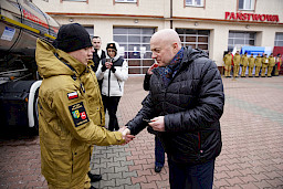 Uroczyste przekazanie sprzętu Straży Pożarnej w Radzyniu Podlaskim. Marszałek Jarosław Stawiarski przekazuje kluczyki do przekazywanych wozów strażackich.