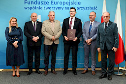 Uroczyste wręczenie umów o dofinansowanie projektów z funduszy europejskich na Integrację społeczną osób najbardziej potrzebujących wsparcia. Marszałek Jarosław Stawiarski z Beneficjentem projektu, który trzyma wręczoną umowę w dłoni.