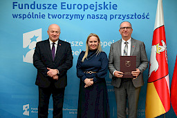 Uroczyste wręczenie umów o dofinansowanie projektów z funduszy europejskich na Integrację społeczną osób najbardziej potrzebujących wsparcia. Marszałek Jarosław Stawiarski z Beneficjentem projektu, który trzyma wręczoną umowę w dłoni.