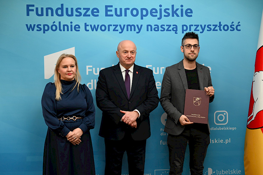 Uroczyste wręczenie umów o dofinansowanie projektów z funduszy europejskich na Integrację społeczną osób najbardziej potrzebujących wsparcia. Marszałek Jarosław Stawiarski z Beneficjentem projektu, który trzyma wręczoną umowę w dłoni.