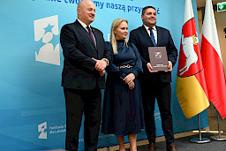 Uroczyste wręczenie umów o dofinansowanie projektów z funduszy europejskich na Integrację społeczną osób najbardziej potrzebujących wsparcia. Marszałek Jarosław Stawiarski z Beneficjentem projektu, który trzyma wręczoną umowę w dłoni.