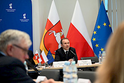 XVII Posiedzenie grup roboczych działających przy Komitecie Monitorującym Fundusze Europejskie dla Lubelskiego 2021-2027, na pierwszym planie członek prezydium, w tle flagi.