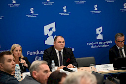 XVII Posiedzenie grup roboczych działających przy Komitecie Monitorującym Fundusze Europejskie dla Lubelskiego 2021-2027, na pierwszym planie prezydium, w tle ścianka Funduszy Europejskich.