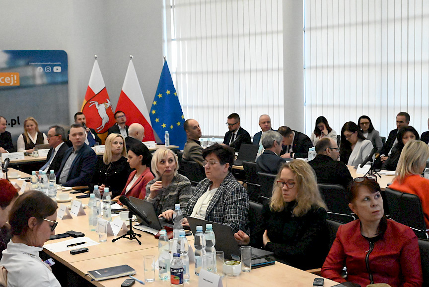 XXXVIII Posiedzenie Komitetu Monitorującego Regionalny Program Operacyjny Województwa Lubelskiego, na pierwszym planie uczestnicy spotkania, w tle prezydium oraz flagi.