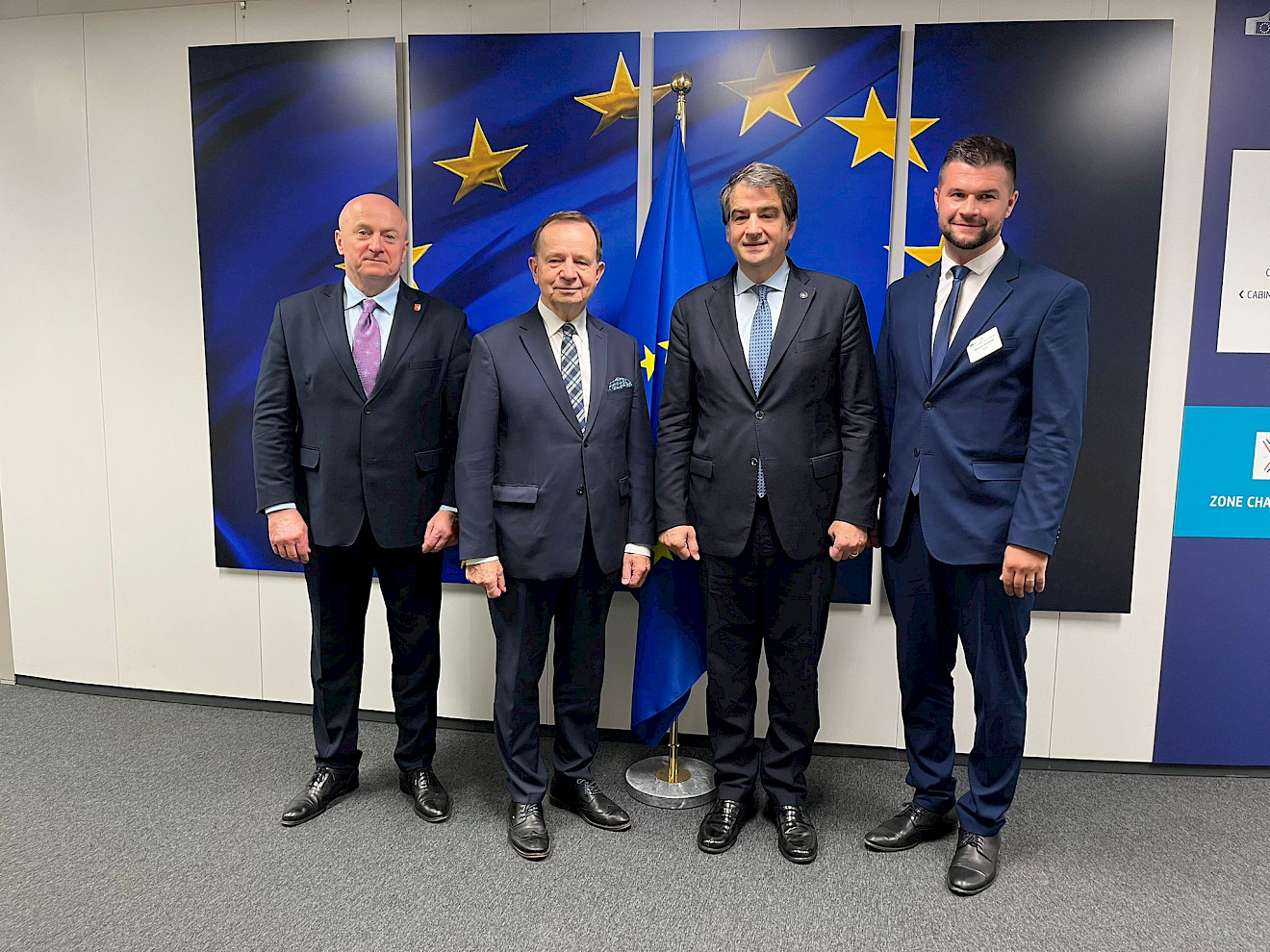 Spotkanie Marszałka Jarosława Stawiarskiego z Raffaele Fitto. W tle flaga Unii Europejskiej, złote gwiazdki  na niebieskim tle.