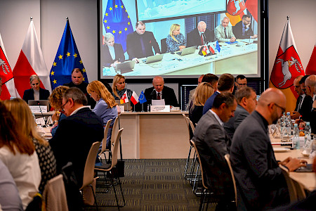 XXI posiedzenie Komitetu Monitorującego Fundusze Europejskie dla Lubelskiego 2021-2027. Sala posiedzeń. Stół prezydendialny, członkowie komitetu.