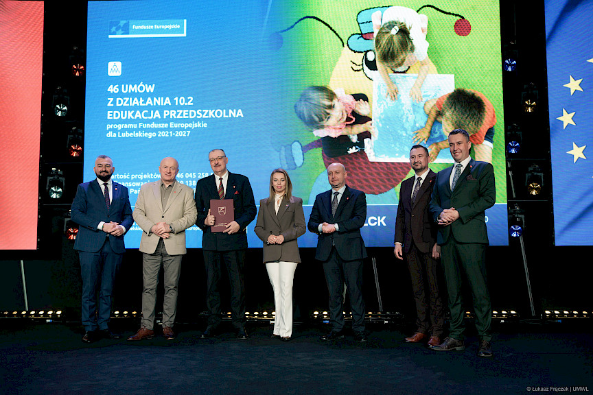 Zdjęcie Zarządu Województwa Lubelskiego z beneficjentem projektu. Ten trzyma teczkę z podpisaną umową. 