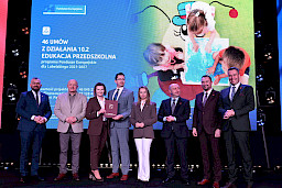 Zdjęcie Zarządu Województwa Lubelskiego z beneficjentami projektu. Kobieta i mężczyzna wspólnie trzymają teczkę z umową.