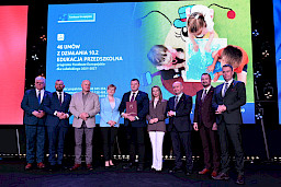 Zdjęcie Zarządu Województwa Lubelskiego z beneficjentami projektu. Mężczyzna trzyma teczkę z umową.