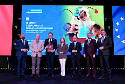 Zarząd Województwa Lubelskiego pozuje do zdjęcia z beneficjentem projektu. Mężczyzna trzyma teczkę w umową.