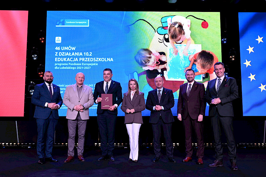 Zarząd Województwa Lubelskiego pozuje do zdjęcia z beneficjentem projektu. Mężczyzna trzyma teczkę w umową.