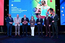 Zarząd Województwa Lubelskiego pozuje do zdjęcia z beneficjentem projektu. Mężczyzna trzyma teczkę w umową.
