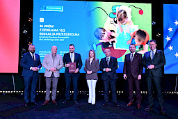 Zarząd Województwa Lubelskiego pozuje do zdjęcia z beneficjentami projektu. Mężczyzna trzyma teczkę w umową.