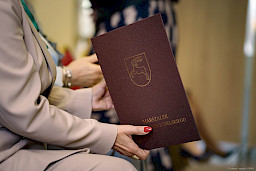 Ujęcie kobiecych dłoni trzymających bordową teczkę ze znakiem województwa lubelskiego koziołkiem oraz napisem złotymi literami Marszałek Województwa Lubelskiego