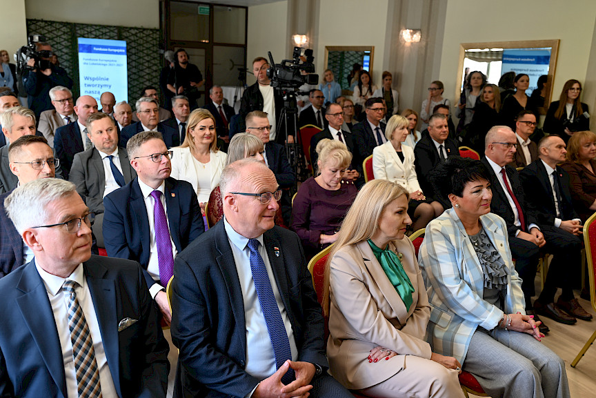 Ogólne ujęcie na salę z siedzącymi uczestnikami spotkania.
