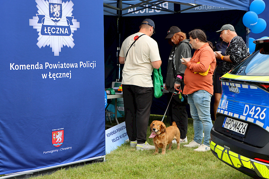 Trzech mężczyzn oraz kobieta z psem stoją przy stoisku komendy powiatowej policji w Łęcznej.