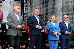 Przedstawiciel gminy Łęczna wypowiada się na scenie do mikrofonu, obok niego stoi Marszałek Jarosław Stawiarski oraz Dyrektor Anna Brzyska.