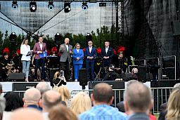 Marszałek Województwa Lubelskiego przemawia ze sceny. Obok niego stoi Dyrektor Anna Brzyska, Przedstawiciele Miasta Łęczna oraz prowadzący wydarzenie. Przed sceną widać część publiczności.