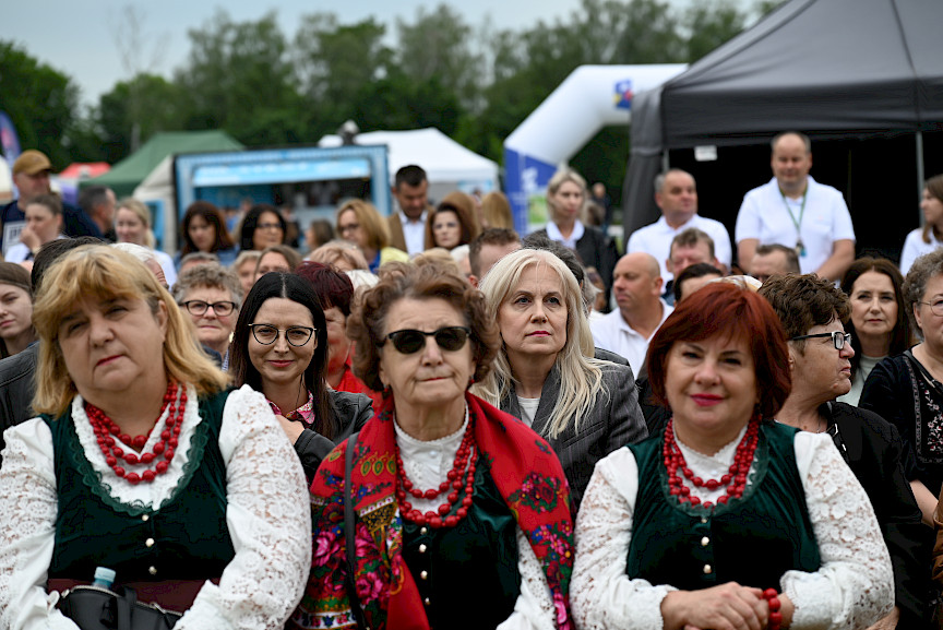 Tłum ludzi przed sceną, na pierwszym planie kobiety z w strojach ludowych, w tle namioty wystawców.