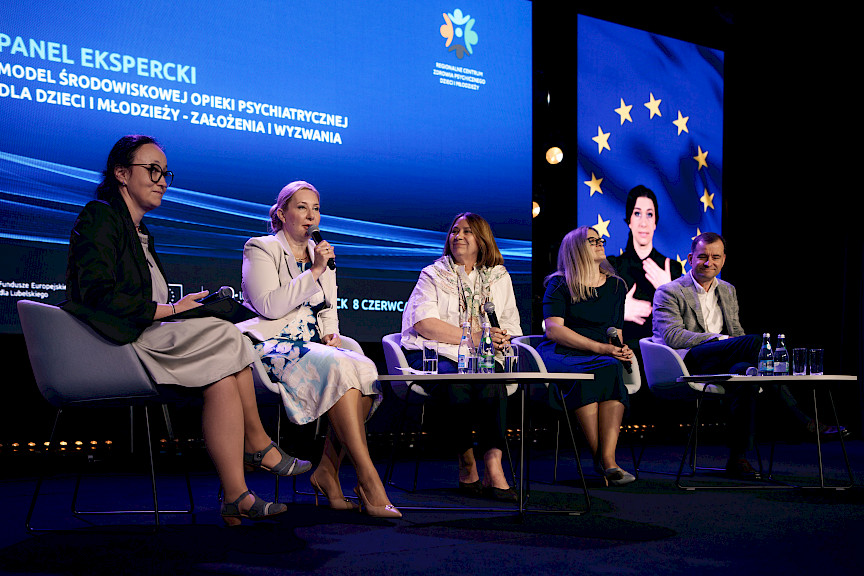 Cztery kobiety oraz mężczyzna siedzą na scenie na krzesłach i prowadzą panel dyskusyjny.